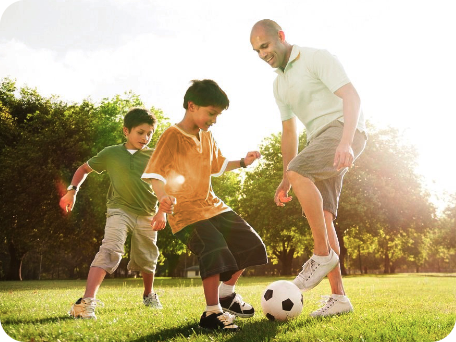 Father playing soccer with his two sons on a sunny afternoon